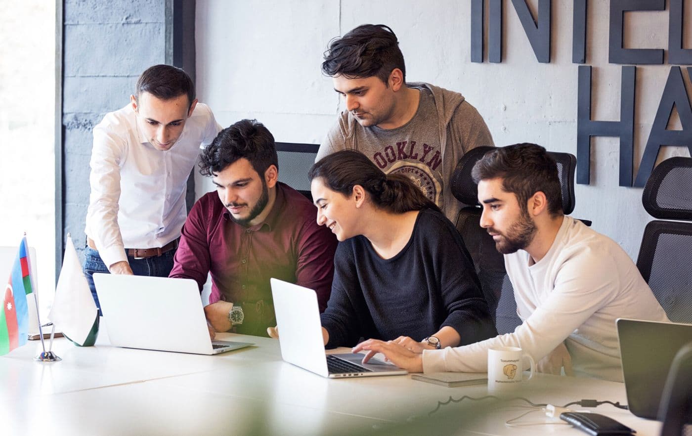 Industrio Capital team collaborating around laptops in the office