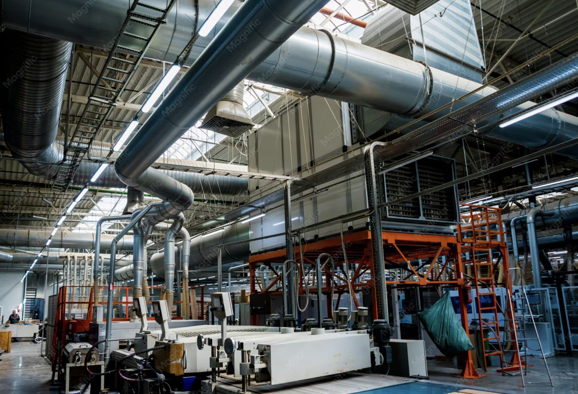 Industrial production hall with overhead ventilation ducts and processing machinery
