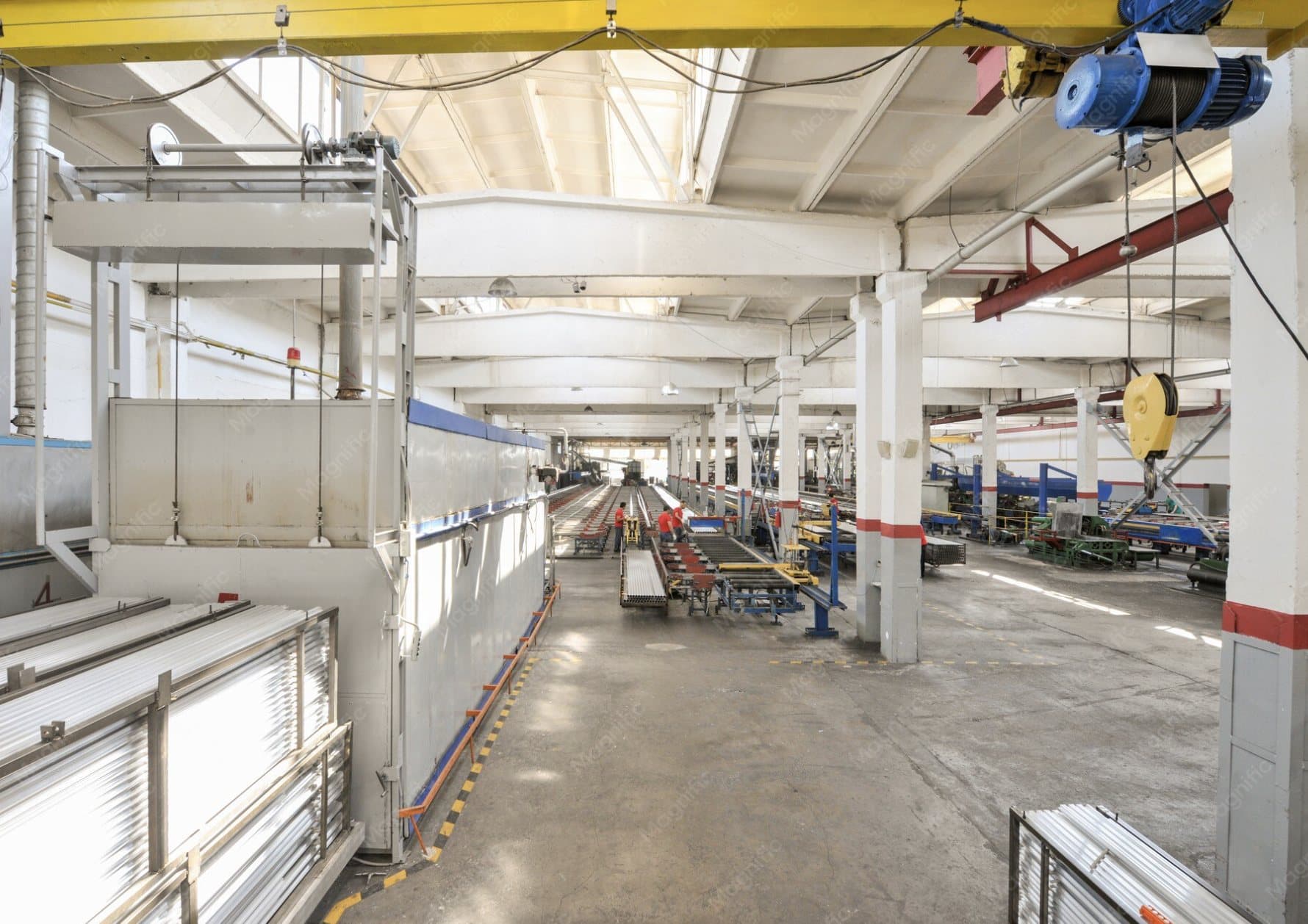 Industrial production hall with overhead cranes and a central roller conveyor line