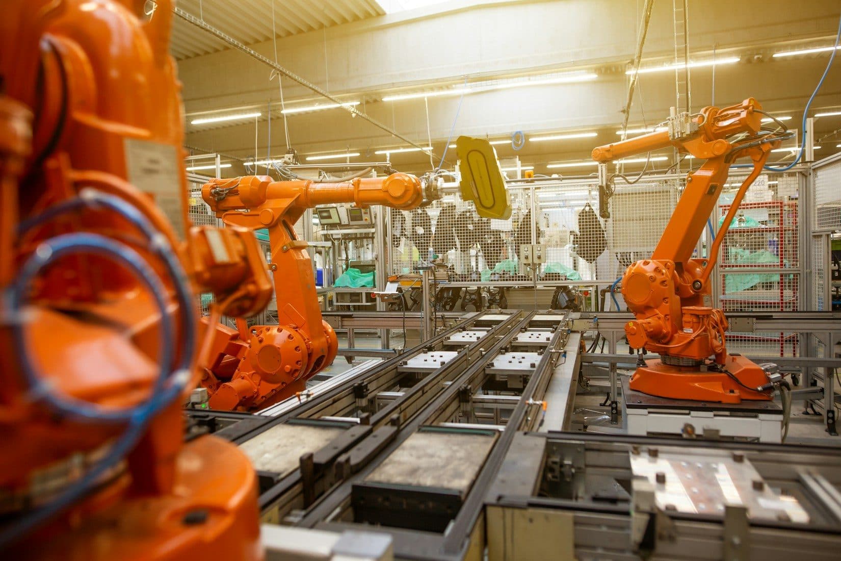 Orange industrial robot arms working along an automated production line